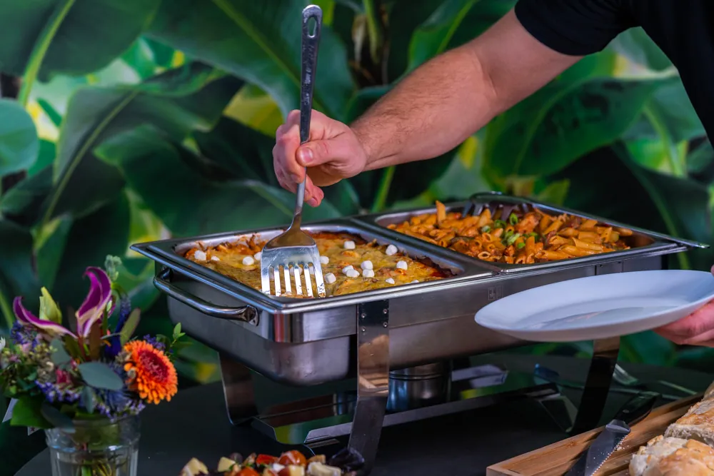 Een warme ovenschotel wordt opgeschept uit een chafing dish