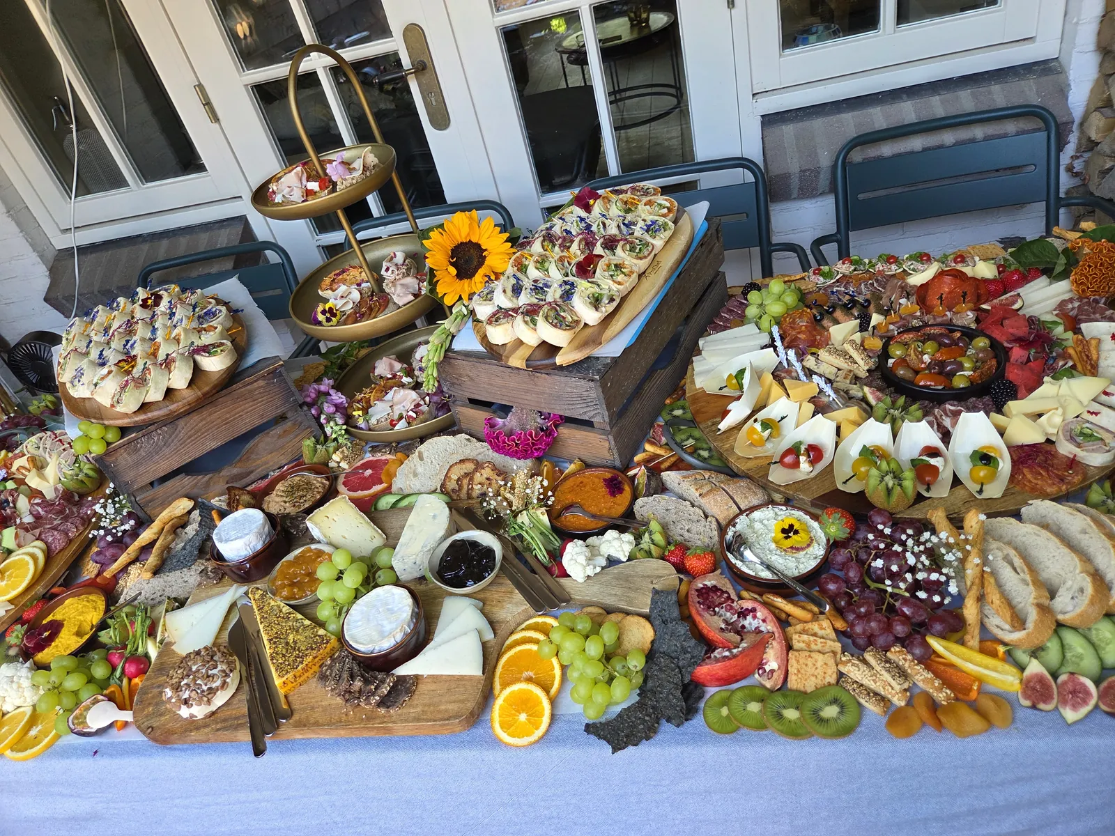 Grazing table buiten met zonnebloemen, houten kistjes en gevulde planken