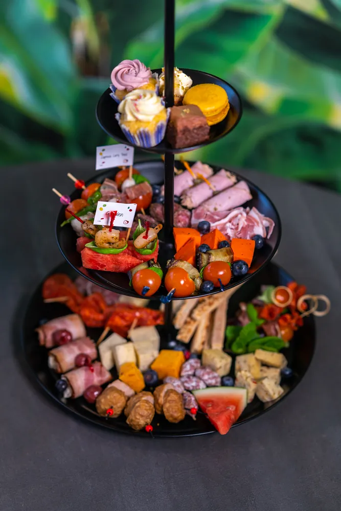 Drielaagse etagère met hartige hapjes, vleeswaren en zoete lekkernijen voor de high tea