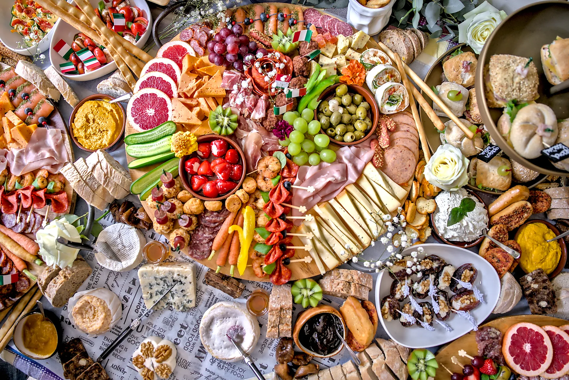 Rijk gevulde grazing table van De keuken van Elise met antipasti, kazen, fruit en bloemen, van bovenaf gefotografeerd